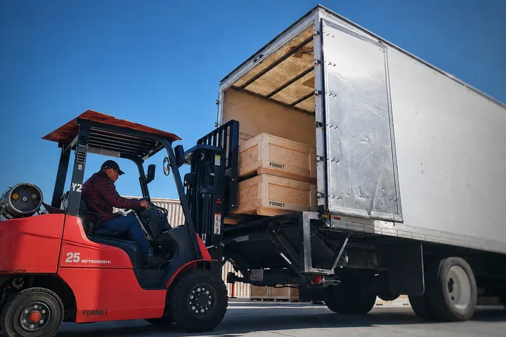 Forklift loading wooden crates into a truck for shipment